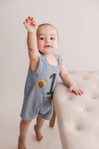 baby boy standing with a 1 romper