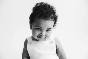 black and white photo of shy baby boy smiling