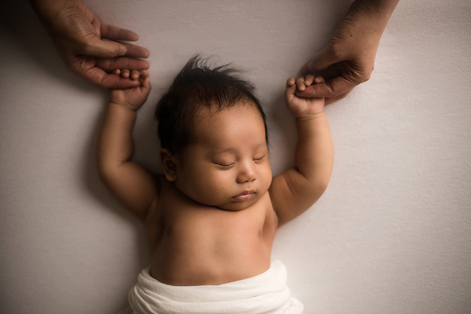 sleeping newborn baby holding parent's hands