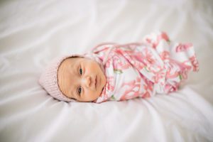 swaddled newborn baby on bed lifestyle raleigh