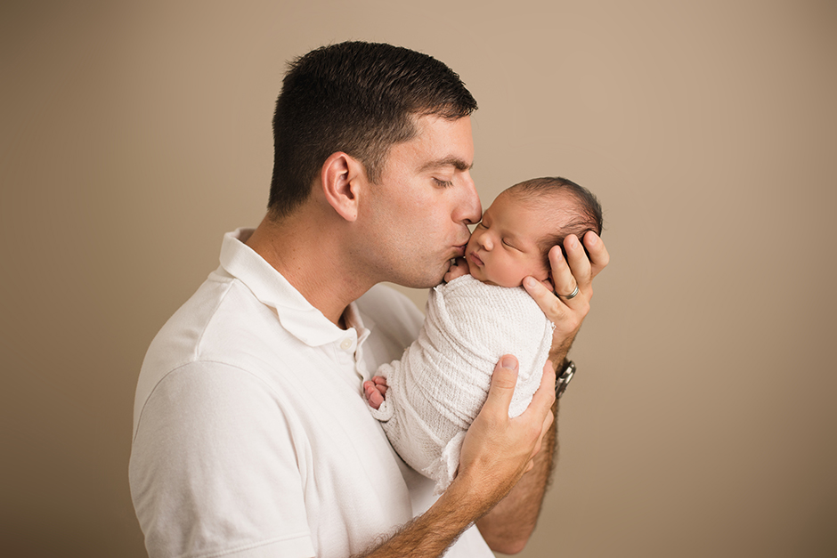 dad kissing newborn baby