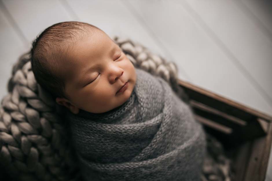 Swaddled newborn baby in grey