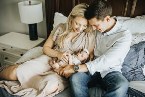 parents holding newborn baby in bed, lifestyle baby photos in clayton