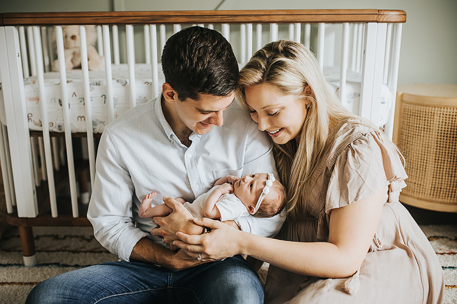 parents holding newborn in front of crib, lifestyle baby photos clayton