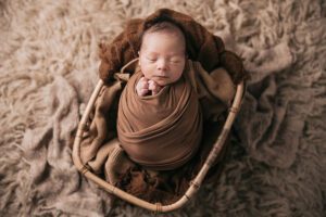 Baby swaddled in basket- holly springs studio newborn pictures