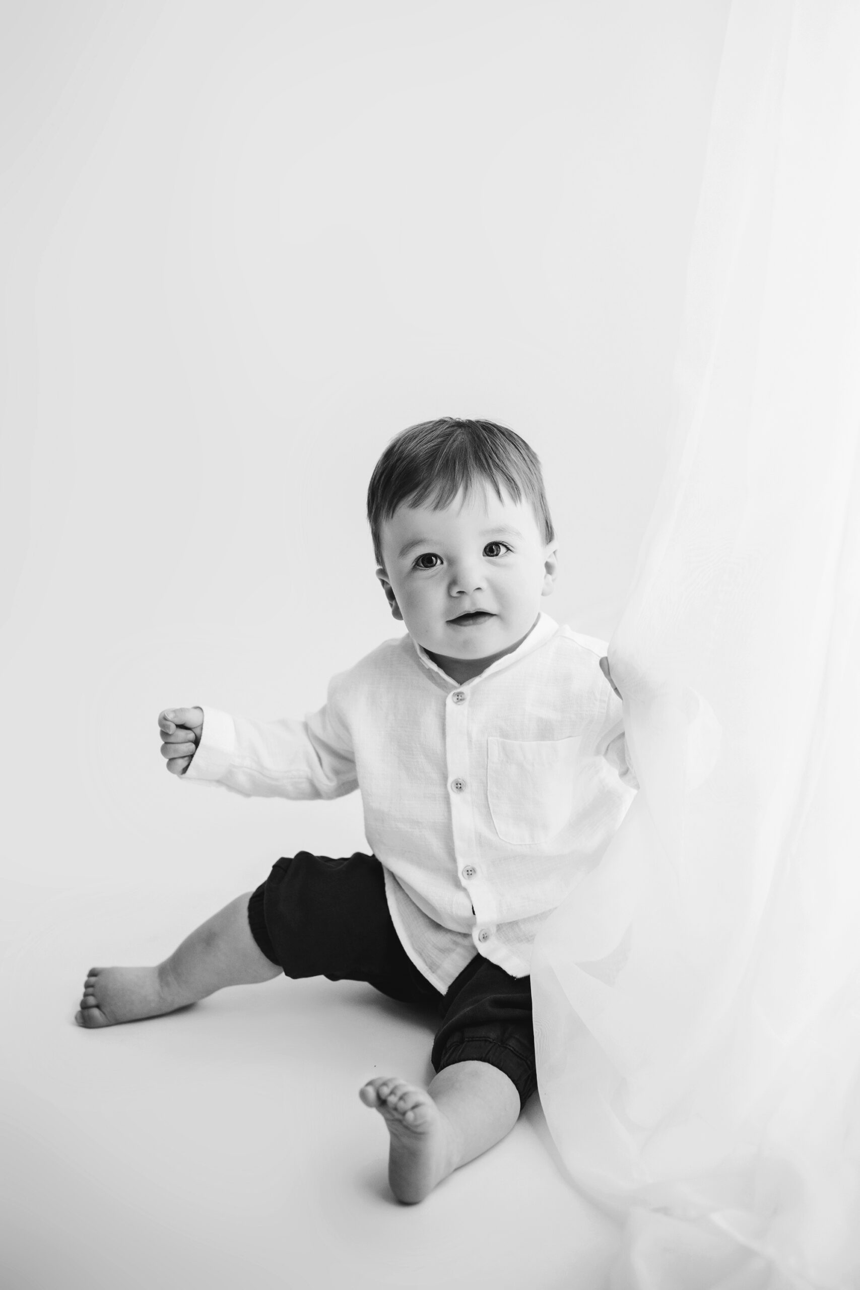 cary baby photographer Laura Karoline phography, baby playing with curtain black and white