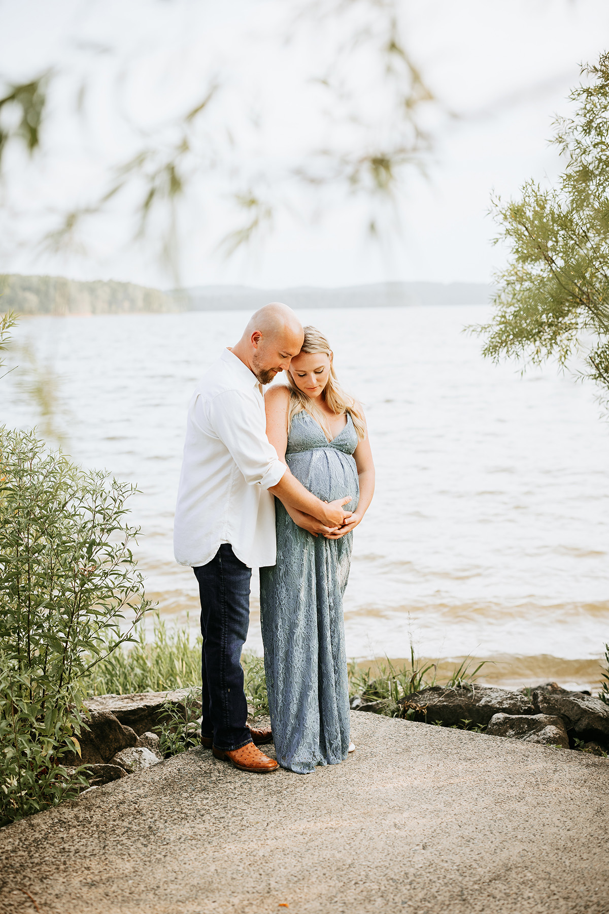 pregnant couple by lake looking down at belly, jordan lake maternity photos, laura karoline photography