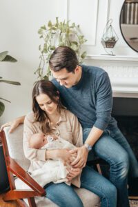 mom and dad sitting looking at newborn baby, Holly Springs Lifestyle Newborn Photos, Laura Karoline Photography