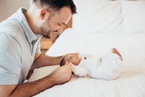 dad playing with newborn on bed- Raleigh in-home newborn photos