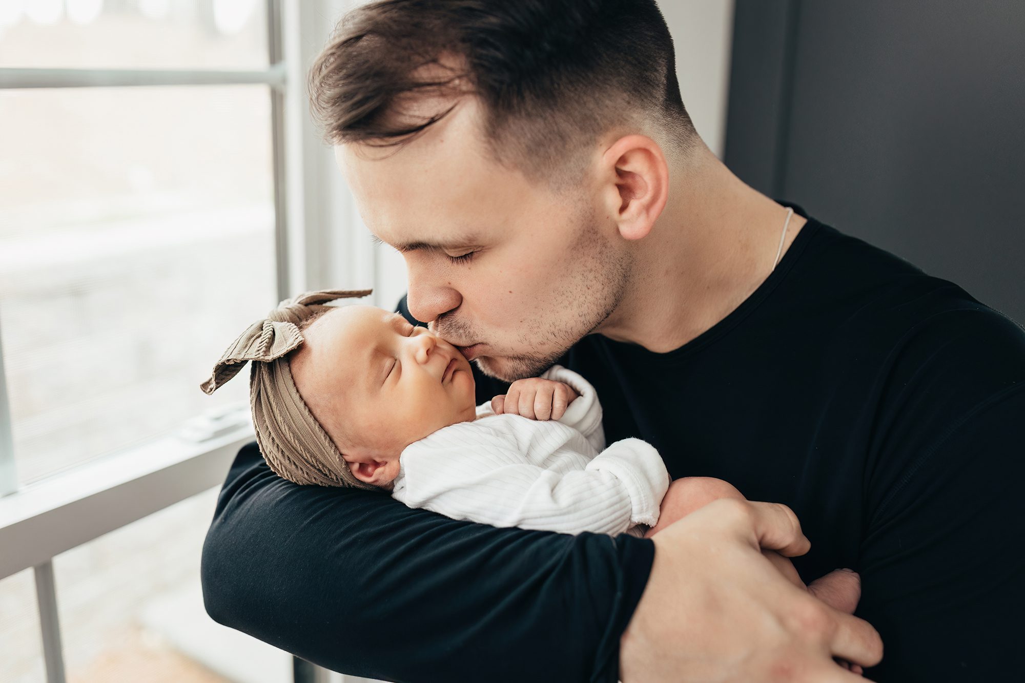 lifestyle newborn photos in apex, dad kissing newborn baby