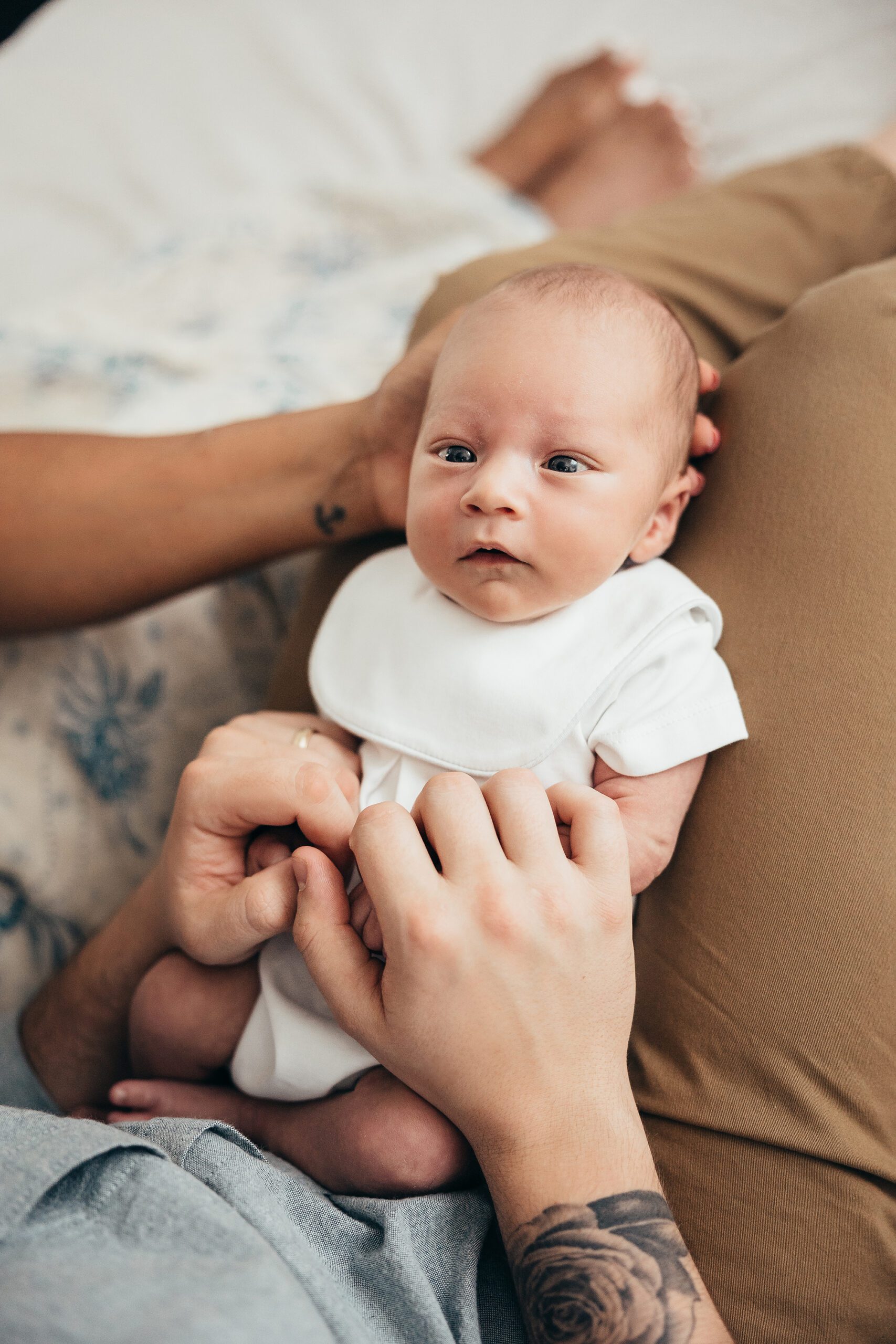 newborn baby in mom and dad's lap with eyes open, raleigh in-home newborn photographer