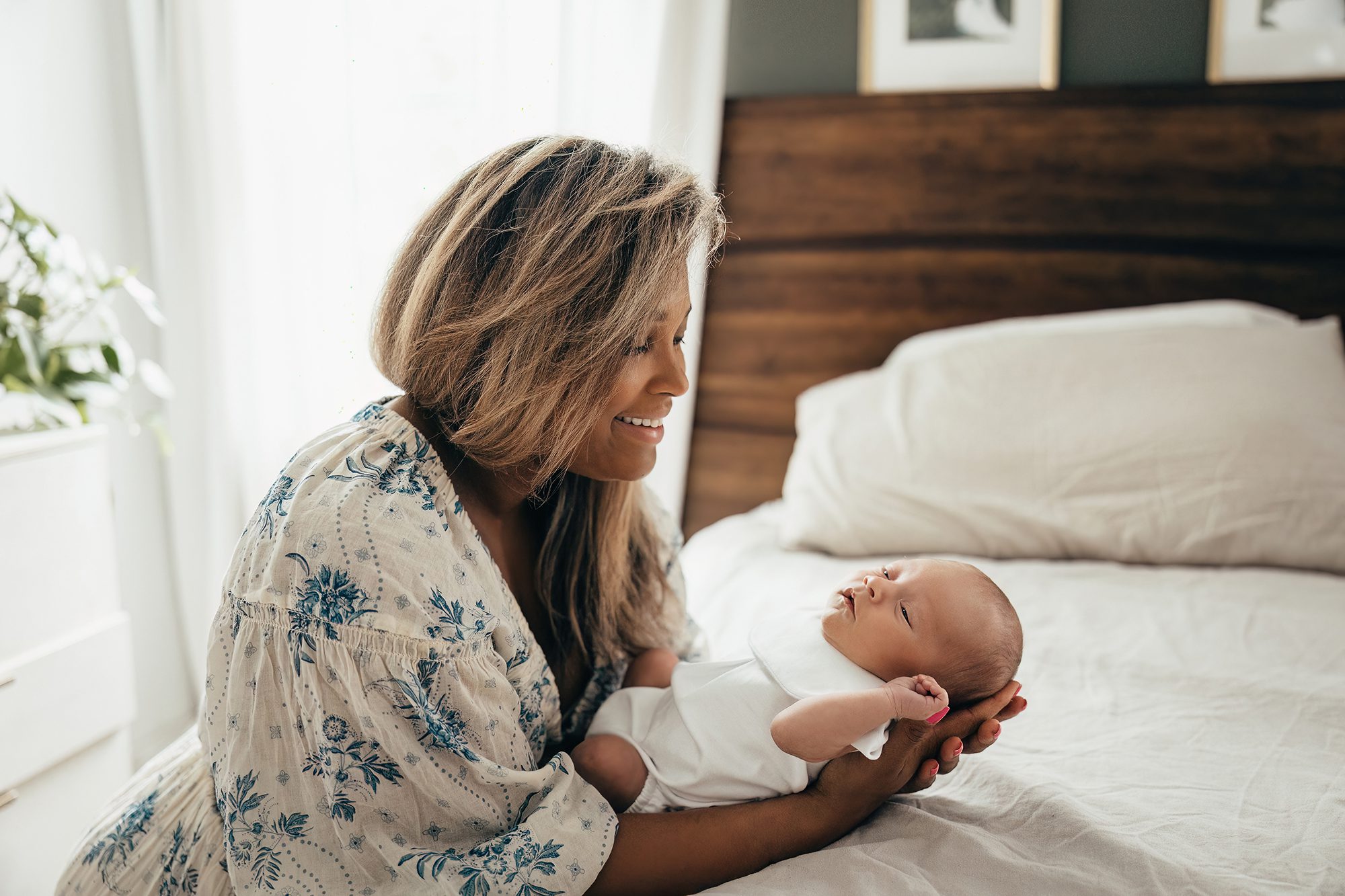 mom and newborn baby smiling, moody in-home newborn photography in raleigh