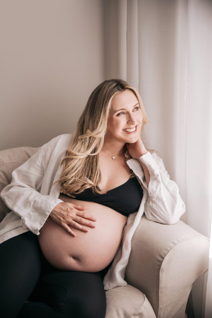pregnant woman relaxing on couch and smiling out the window