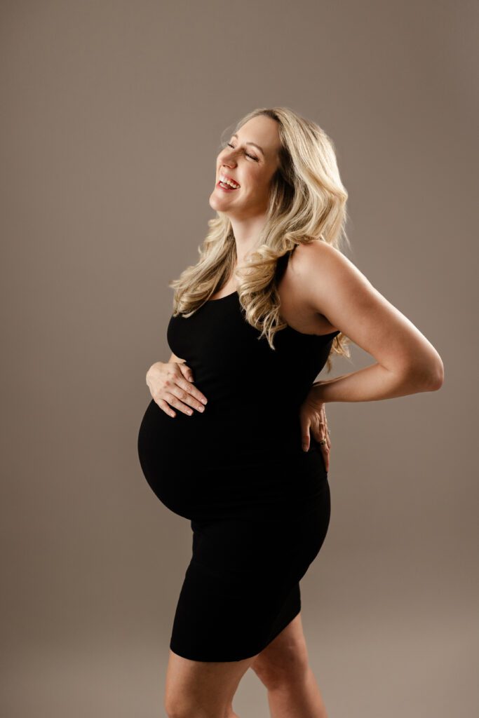 beautiful pregnant mom laughing dressed in black dress