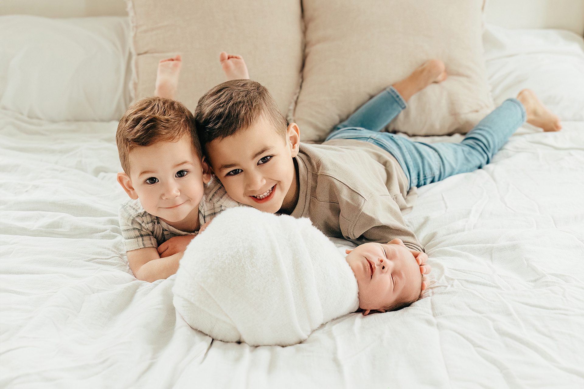three brothers in a newborn photoshoot laying on bed
