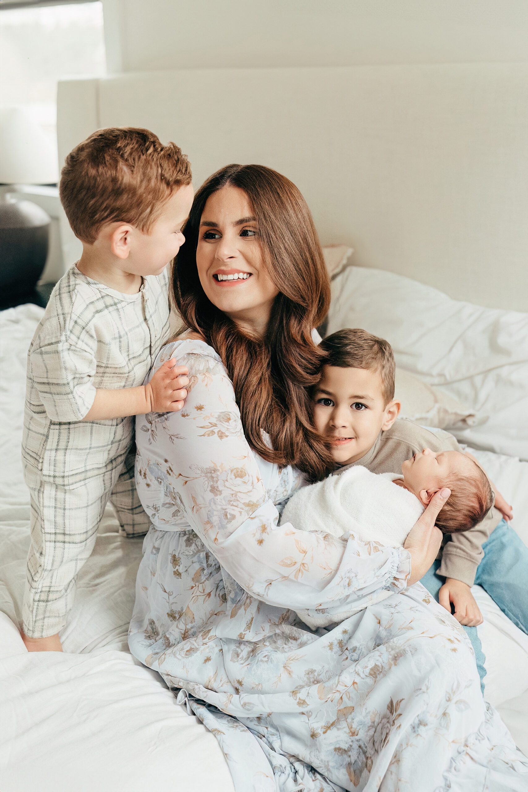 mom with newborn and two sons sitting on bed