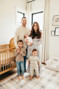 family of five with newborn posing in nursery