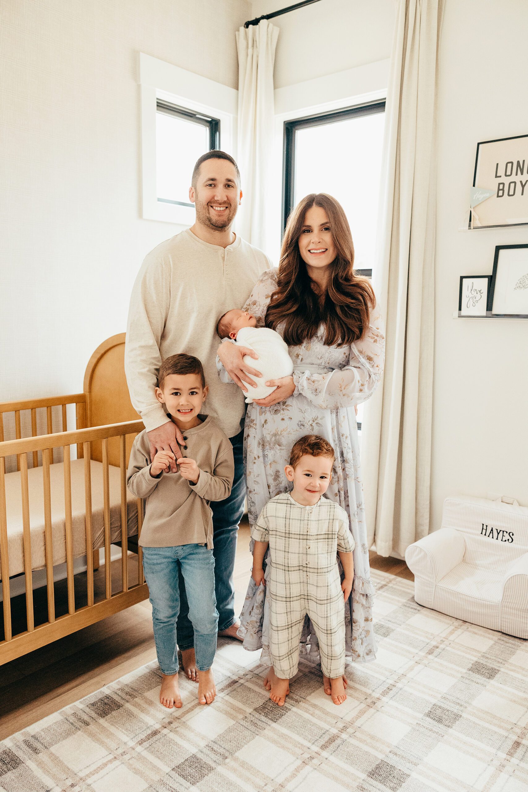 family of five with newborn posing in nursery