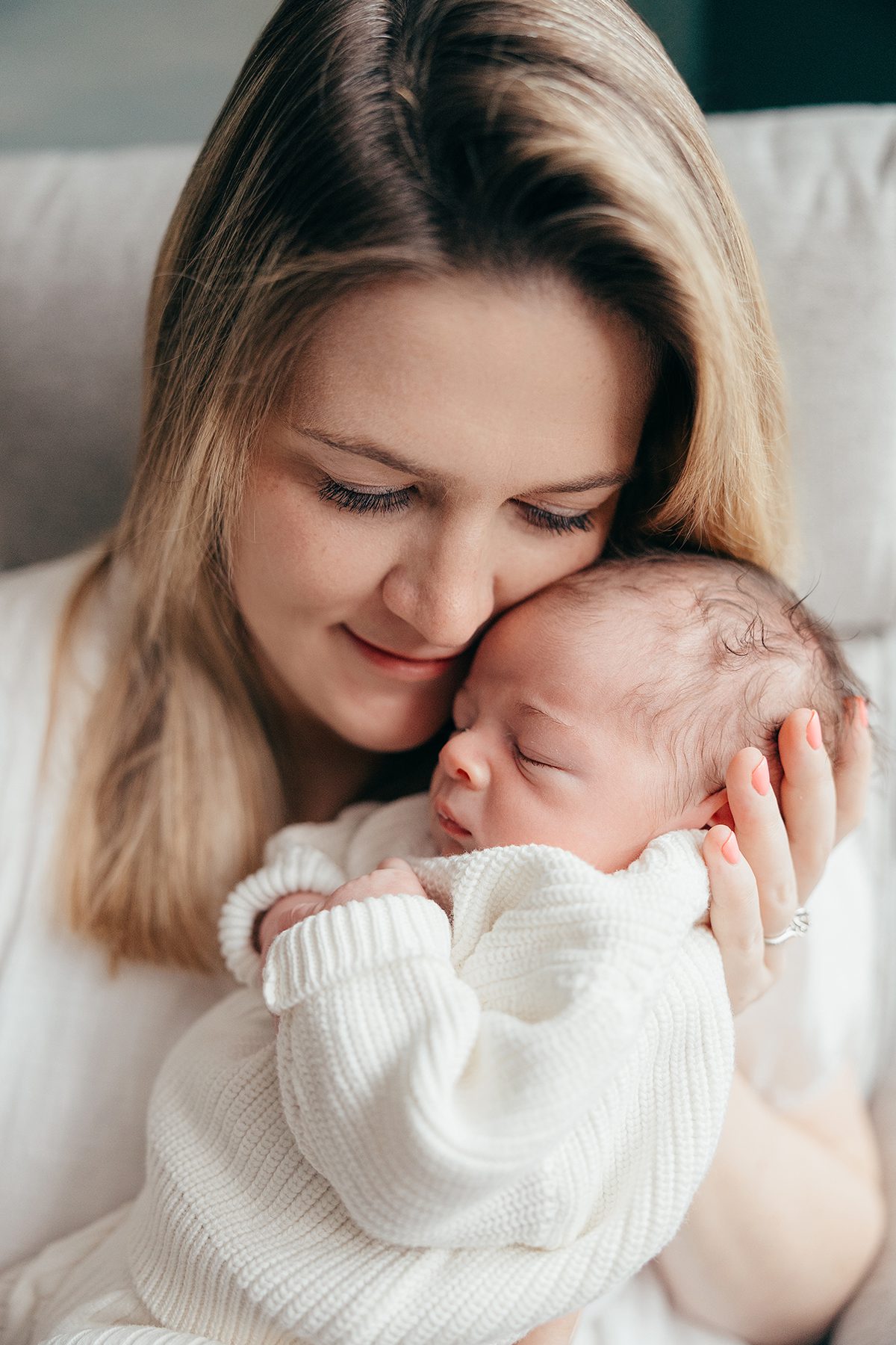 mom snuggling with newborn baby dressed in white. cary in home photography