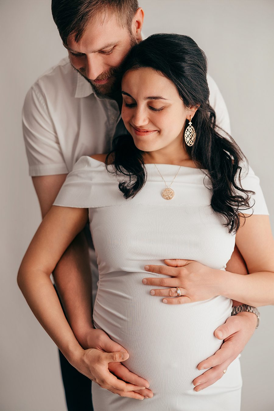pregnant mom and dad embracing in white clothing